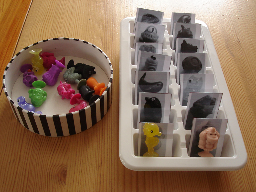 Bunte Figuren, die in einen Behälter mit kleinen Abteilungen einsortiert werden können